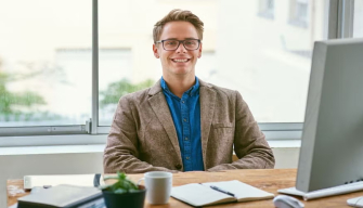 A confident professional man sits at a desk with a computer, representing the qualities of good public policy