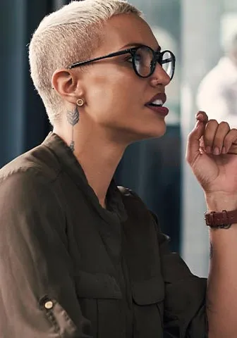 A woman wearing glasses sits at a desk, focused on her computer screen.