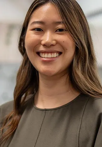 A smiling young woman sitting at her desk in a bright office environment.