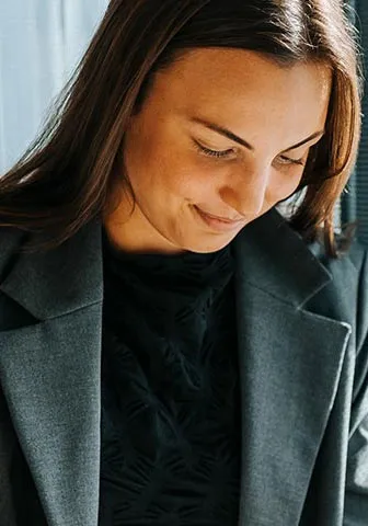 A woman speaks to another woman in an office setting, both engaged in a professional conversation.