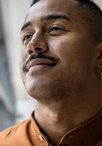 A man gazes thoughtfully out of a window, contemplating the view beyond.