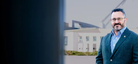 1. A man wearing glasses and a suit stands confidently in front of a modern building.