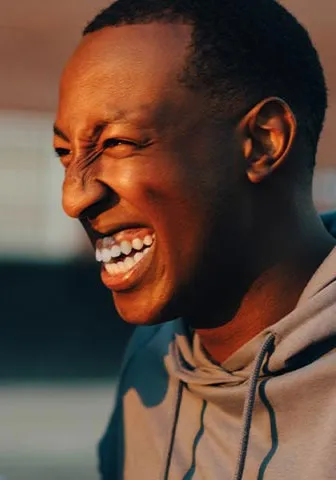 Two young men smiling and laughing together, enjoying a joyful moment in a casual setting.