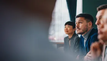 1. A diverse group of professionals seated around a conference table in a meeting room, engaged in discussion.