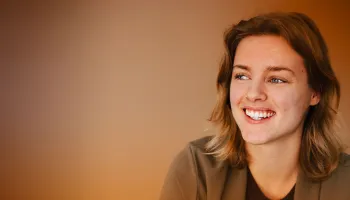 A woman with closed eyes smiles warmly, conveying joy and contentment.