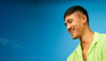 A man wearing a green shirt is smiling warmly at the camera.