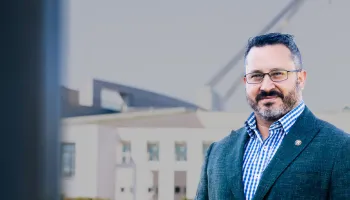 1. A man wearing glasses and a suit stands confidently in front of a modern building.