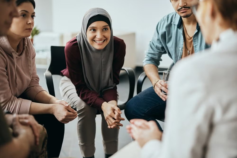 A diverse group of people sit in a supportive circle discussion, representing case management in social work