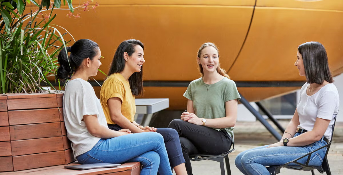 Four female students sit in a circle outdoors, representing the benefits of studying public policy at university