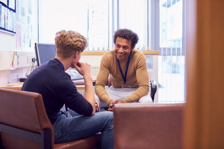 A school counsellor sits attentively with a student in a supportive one-on-one session.