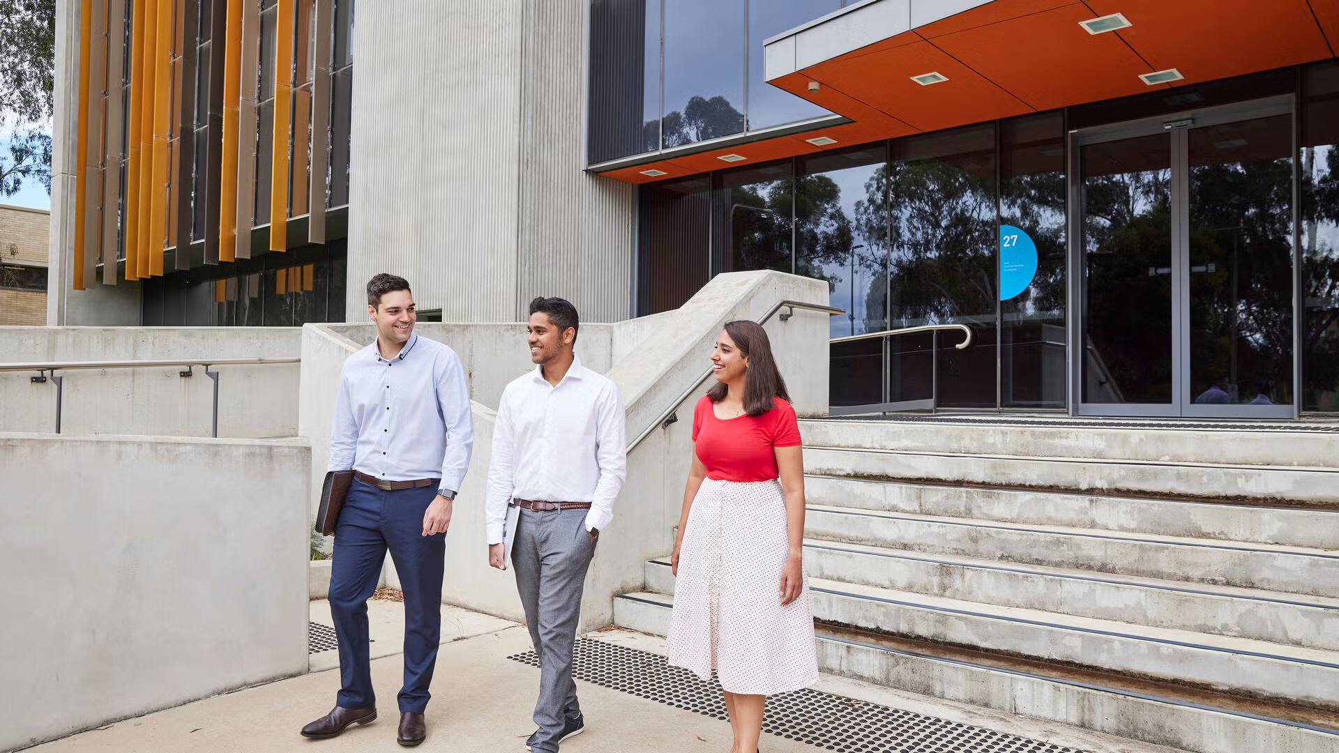 Three students walk together outside a university building, representing what public policy is and who studies it