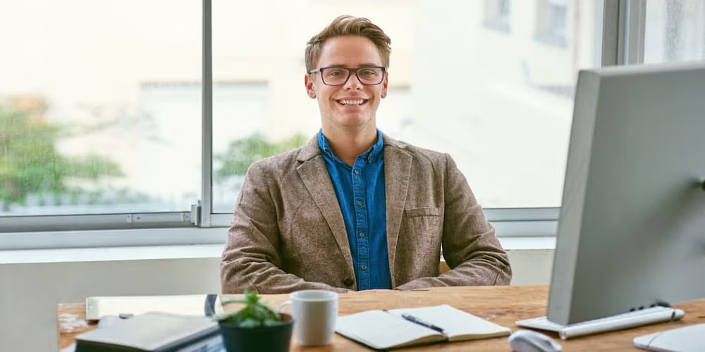 A confident professional man sits at a desk with a computer, representing the qualities of good public policy