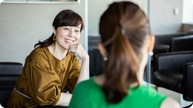 A woman and another woman sitting together at a table, engaged in conversation.