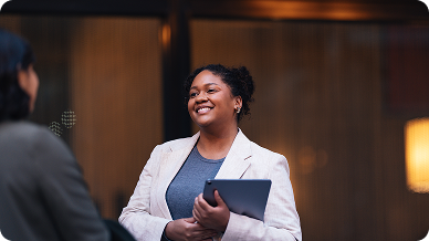 A woman in a business suit engages in conversation with another woman in a professional setting.